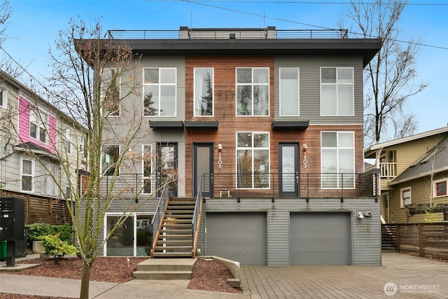 view of front of house with stairs, decorative driveway, fence, and a garage