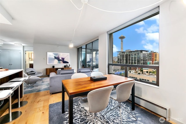 dining area with baseboard heating, wood-type flooring, and a city view