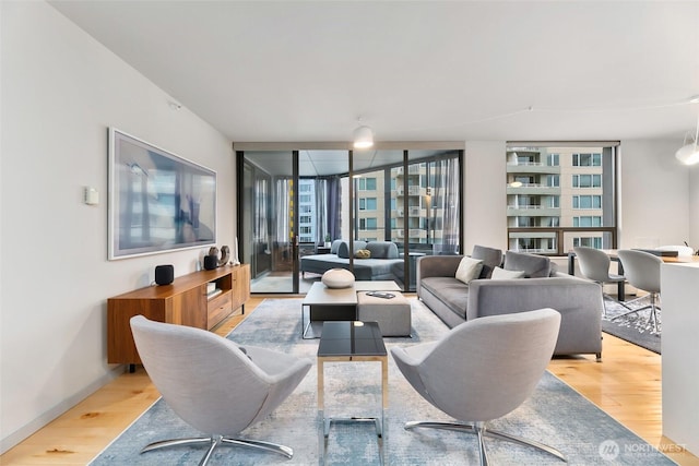 living room featuring a wall of windows, plenty of natural light, and light wood-style floors