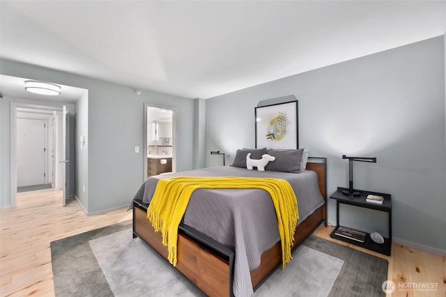 bedroom featuring a sink, connected bathroom, baseboards, and wood finished floors