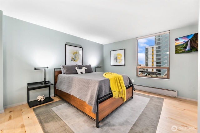 bedroom with baseboards, baseboard heating, wood finished floors, and a city view