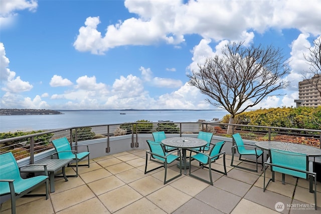 view of patio / terrace featuring outdoor dining area, a water view, and a balcony