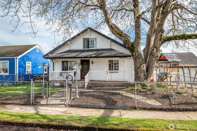 bungalow-style house featuring covered porch, a fenced front yard, a playground, and a gate