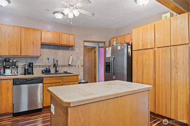 kitchen featuring tile counters, decorative backsplash, appliances with stainless steel finishes, a textured ceiling, and a sink