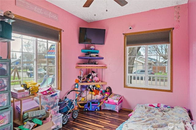 bedroom featuring a textured ceiling, multiple windows, wood finished floors, and a ceiling fan