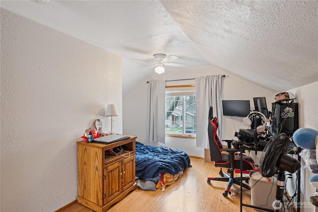 interior space featuring a textured ceiling, a textured wall, light wood finished floors, and lofted ceiling