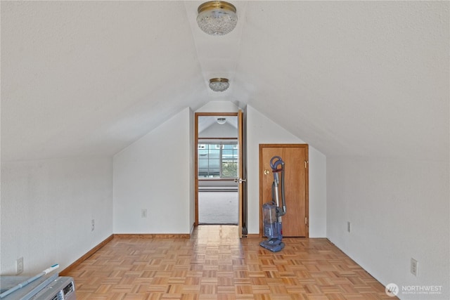 bonus room with a textured ceiling, vaulted ceiling, and baseboards