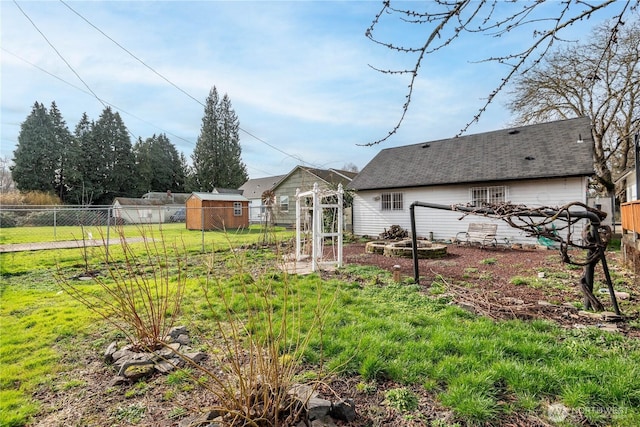 view of yard featuring a garden, fence, and an outbuilding