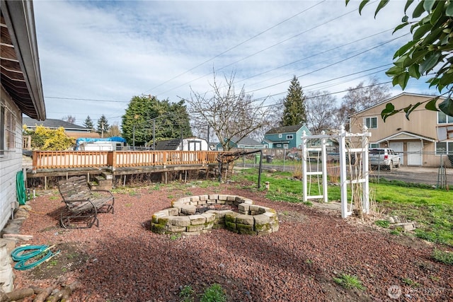 view of yard featuring an outdoor fire pit, fence, and a wooden deck