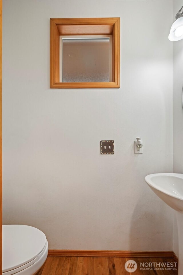 bathroom featuring toilet, baseboards, and wood finished floors