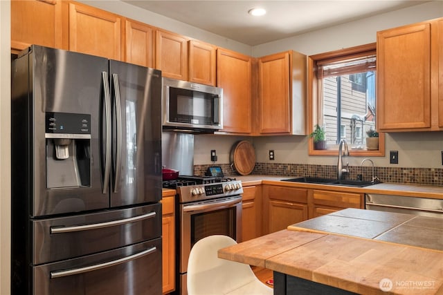 kitchen with tile counters, stainless steel appliances, a sink, and recessed lighting