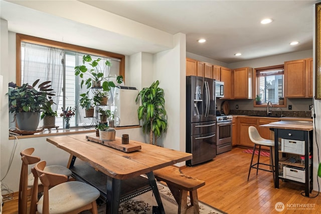 kitchen featuring recessed lighting, stainless steel appliances, a sink, brown cabinets, and light wood finished floors