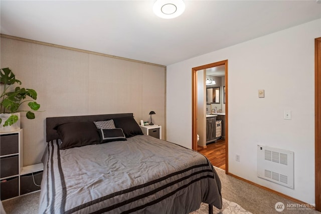 bedroom with ensuite bathroom, carpet floors, and heating unit