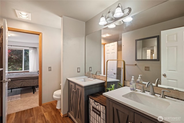 ensuite bathroom with toilet, vanity, ensuite bath, wood finished floors, and baseboards