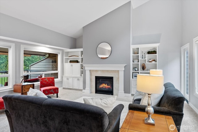 living room with carpet floors, high vaulted ceiling, and a tiled fireplace