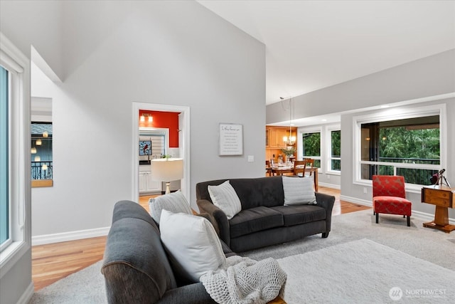 living area with high vaulted ceiling, light wood finished floors, and baseboards