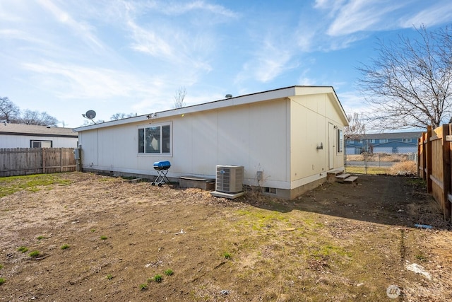 rear view of property with a fenced backyard and central AC unit