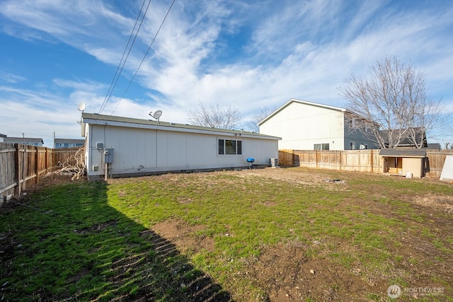 rear view of property featuring a fenced backyard and a lawn