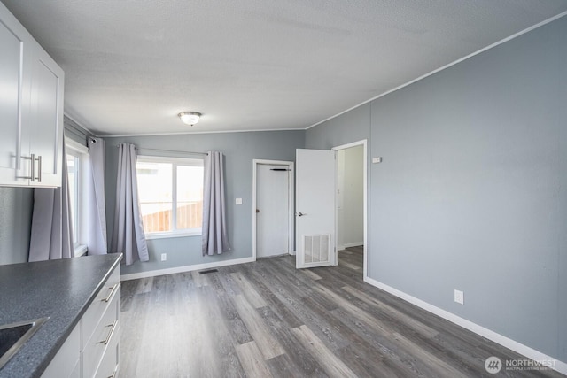 interior space with ornamental molding, dark wood finished floors, visible vents, and baseboards