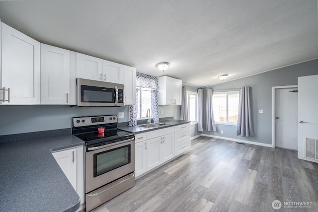 kitchen with appliances with stainless steel finishes, dark countertops, and white cabinetry