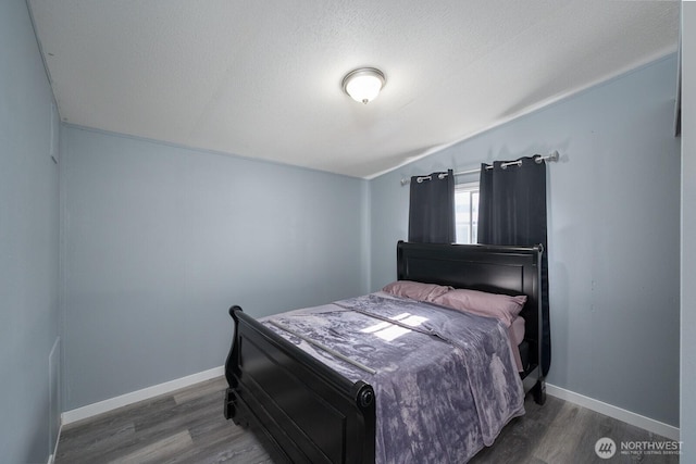 bedroom featuring vaulted ceiling, wood finished floors, and baseboards