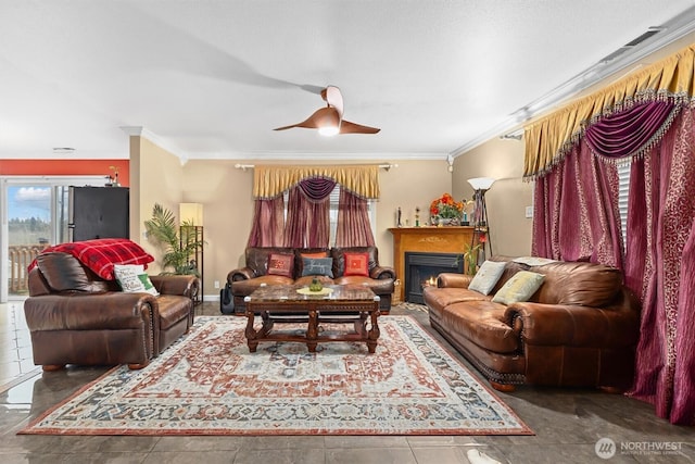 living area with a warm lit fireplace, baseboards, ornamental molding, and a ceiling fan