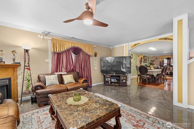 living area with ornamental molding, arched walkways, a fireplace, and ceiling fan