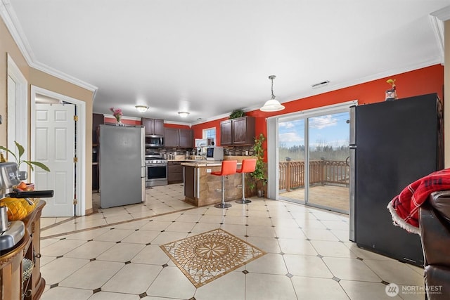 kitchen with appliances with stainless steel finishes, a breakfast bar, light countertops, crown molding, and backsplash