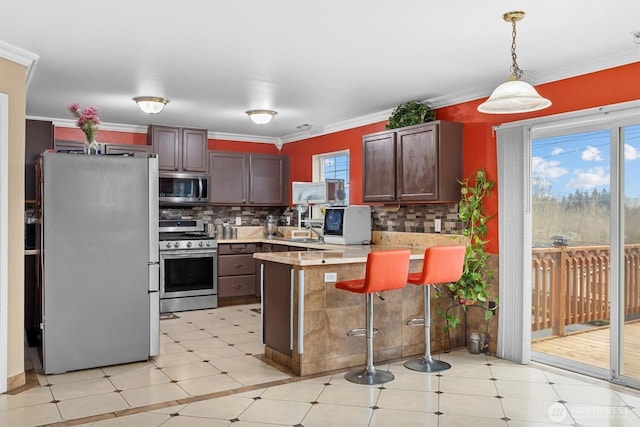 kitchen with appliances with stainless steel finishes, light countertops, crown molding, and a peninsula