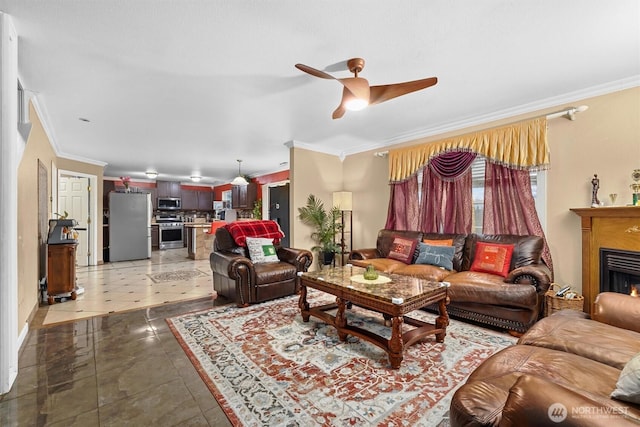 living room featuring a warm lit fireplace, a ceiling fan, and crown molding