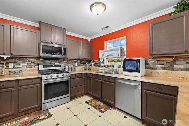 kitchen featuring stainless steel appliances, a sink, visible vents, light countertops, and crown molding