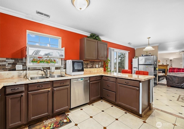 kitchen featuring visible vents, stainless steel appliances, crown molding, light countertops, and a sink