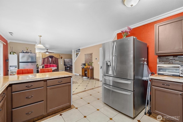 kitchen with stainless steel fridge, ornamental molding, light countertops, and freestanding refrigerator