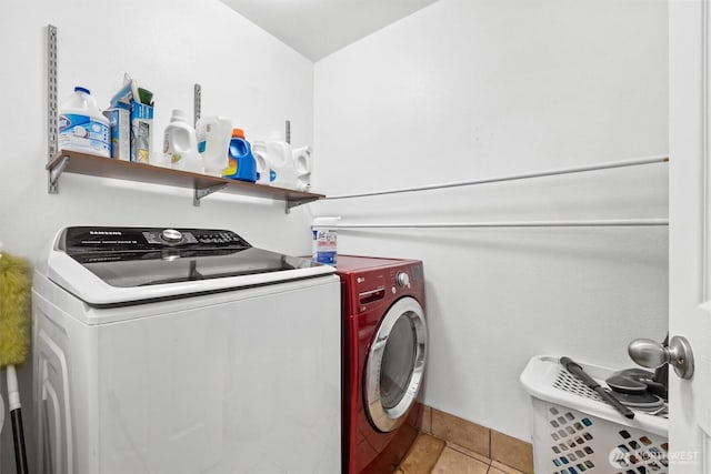 washroom featuring laundry area, light tile patterned flooring, and washing machine and clothes dryer