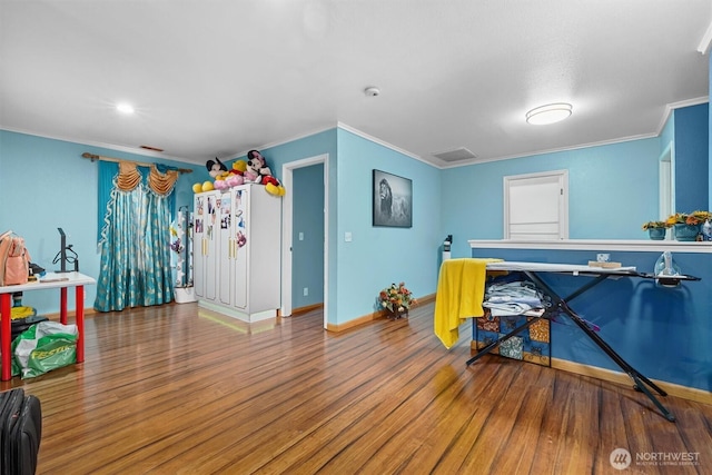 game room with baseboards, wood finished floors, visible vents, and crown molding