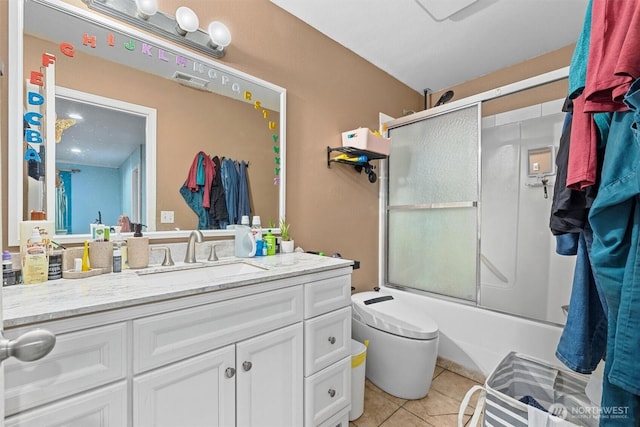 bathroom featuring toilet, combined bath / shower with glass door, tile patterned flooring, and vanity