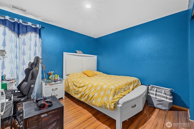 bedroom featuring visible vents and wood finished floors