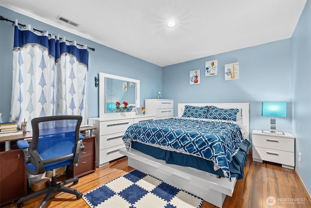 bedroom with visible vents and wood finished floors