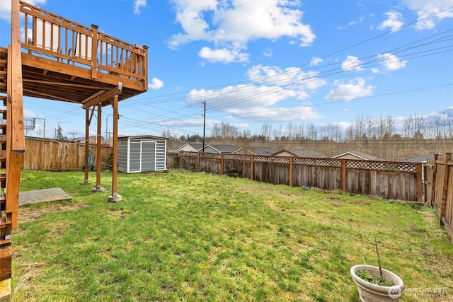 view of yard with an outbuilding, a storage shed, a fenced backyard, and a wooden deck