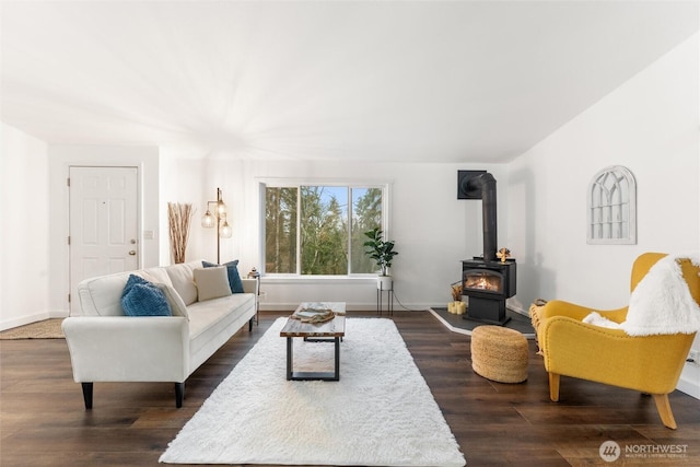 living area with a wood stove, baseboards, and dark wood-style flooring