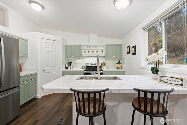 kitchen featuring green cabinets, light countertops, appliances with stainless steel finishes, and decorative backsplash