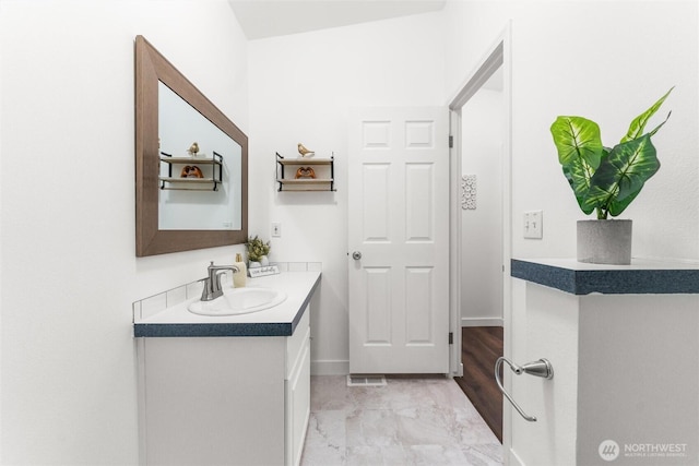 bathroom with marble finish floor, vanity, and baseboards