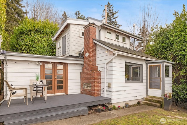 rear view of property featuring entry steps, a shingled roof, a chimney, and a wooden deck