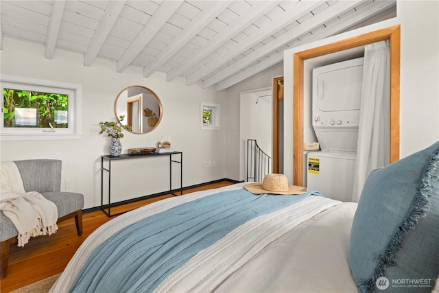 bedroom with lofted ceiling with beams, wooden ceiling, wood finished floors, and stacked washer and clothes dryer