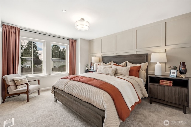 bedroom featuring light carpet, a decorative wall, and visible vents