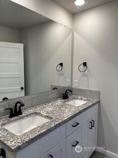 bathroom featuring double vanity, a sink, and baseboards