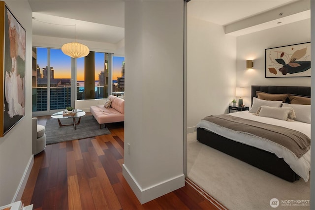 bedroom featuring a view of city, dark wood finished floors, and baseboards