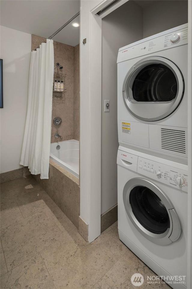 clothes washing area featuring stacked washer and dryer, laundry area, and baseboards