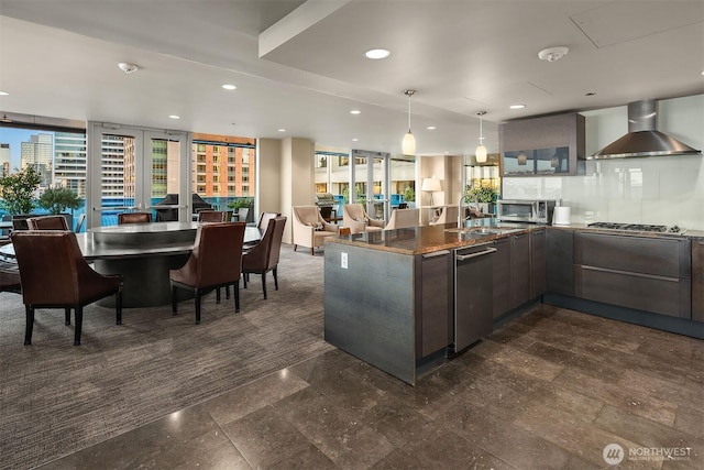 kitchen with a city view, recessed lighting, hanging light fixtures, wall chimney exhaust hood, and modern cabinets