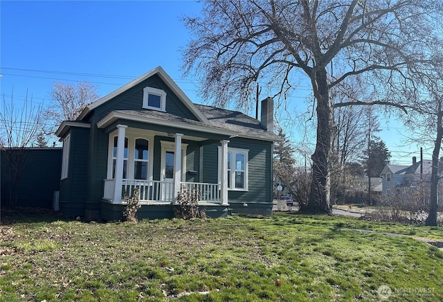 bungalow-style house featuring a porch, a front yard, and a chimney